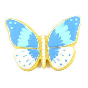 Op de afbeelding: Een gele vlinderkoek versierd met blauwe en witte glazuur. De vlinder heeft een gedetailleerd ontwerp op zijn vleugels.