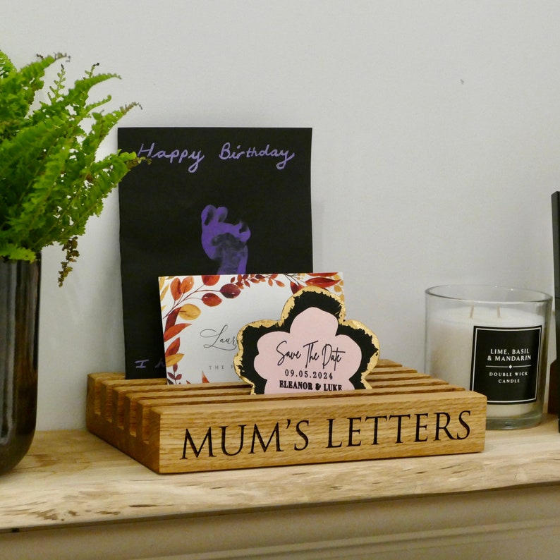 May include: A wooden letter holder with the inscription "MUM'S LETTERS" on the front. The holder has slots for cards and envelopes. There are several cards in the holder, including a birthday card, a save the date card, and a fall-themed card.