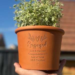 May include: Terracotta flower pot with the words "Engaged" and a heart design. The pot is personalised with the names "Jack & Stewart" and the message "Congratulations! Lots of Love Jill & Stephen xx".