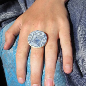 以下が含まれることがあります： 青と白の渦巻き模様が施された白いセラミックリング