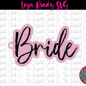 Könnte beinhalten: Ein rosa und schwarzes Laser-Schnittdesign des Wortes "Bride" mit einem kleinen Kreis oben zum Aufhängen.