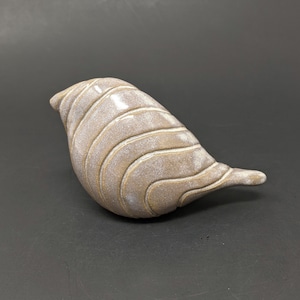 May include: A ceramic bird figurine with a white and brown glaze. The bird has a rounded body and a long, thin tail. The glaze has a textured, wavy pattern.