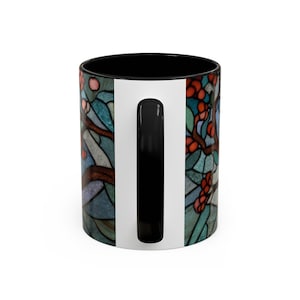 Puede incluir: Taza de caf&eacute; de cer&aacute;mica con interior y asa negros. El exterior presenta un dise&ntilde;o de vidriera con bayas rojas, ramas marrones y hojas azules y verdes. Una franja vertical blanca recorre el lateral.
