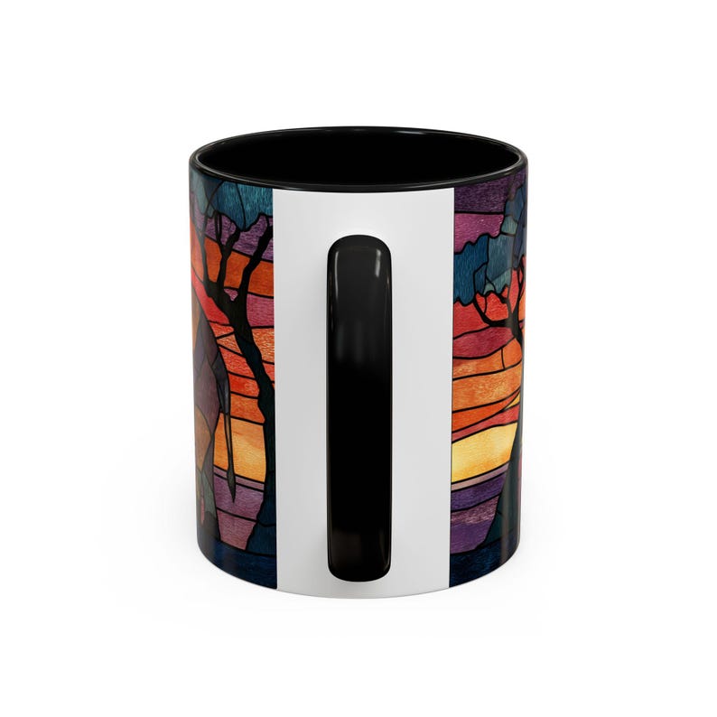 Puede incluir: Una taza de caf&eacute; de cer&aacute;mica con interior y asa negros, con un colorido dise&ntilde;o de vidriera. La obra de arte representa una escena de puesta de sol con &aacute;rboles en tonos naranja, rojo, morado y azul. La taza tiene una franja vertical blanca.