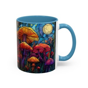 Peut inclure: Une tasse en c&eacute;ramique blanche avec un int&eacute;rieur et une anse bleus. La tasse pr&eacute;sente une illustration color&eacute;e de champignons dans un cadre forestier, avec une pleine lune en arri&egrave;re-plan. Les champignons sont de couleurs vari&eacute;es, dont orange, rouge et violet.