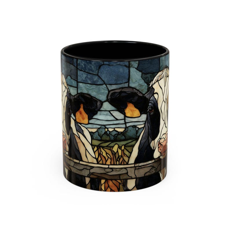 Puede incluir: Una taza de caf&eacute; de cer&aacute;mica con interior negro y dise&ntilde;o de vidriera. El dise&ntilde;o presenta la cara de una vaca con un fondo de paisaje en tonos azules, verdes y naranjas. La taza es cil&iacute;ndrica y tiene un exterior blanco.