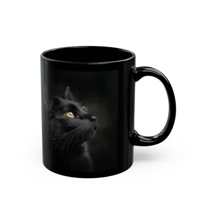 Pu&ograve; includere: Tazza in ceramica nera con il profilo laterale di un gatto nero con occhi gialli. Il gatto &egrave; posto su uno sfondo scuro. La tazza ha un manico curvo.