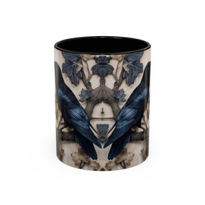 May include: A ceramic coffee mug with a black interior and a wraparound design featuring two dark blue ravens perched on a branch. The background has a beige and gray floral pattern. The mug is cylindrical and has a white exterior.