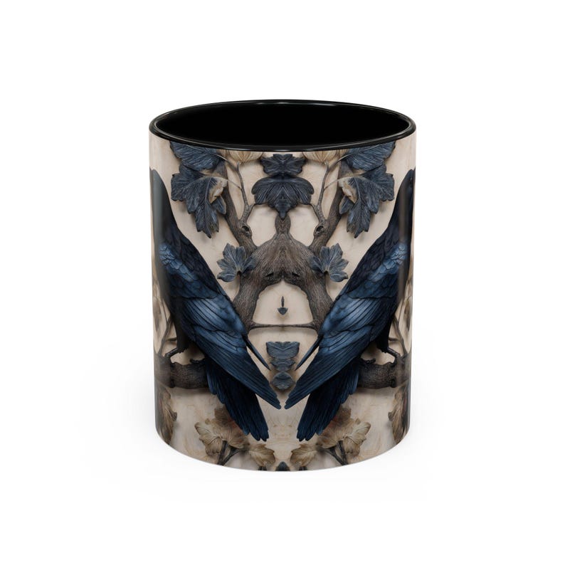May include: A ceramic coffee mug with a black interior and a wraparound design featuring two dark blue ravens perched on a branch. The background has a beige and gray floral pattern. The mug is cylindrical and has a white exterior.