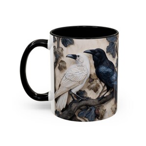 May include: White ceramic mug with a black handle and interior. The mug features a detailed relief of two birds, one white and one black, perched on a branch with leaves. The design has a textured, carved appearance.