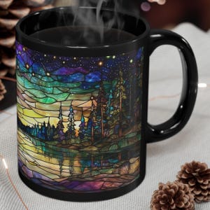 May include: Black ceramic coffee mug with a stained glass design of a forest scene at night. The design features a dark blue sky with stars, a lake reflecting the sky, and a line of trees in the foreground.