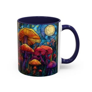 Peut inclure: Mug en c&eacute;ramique blanche avec int&eacute;rieur et anse bleu fonc&eacute;. L'illustration color&eacute;e repr&eacute;sente des champignons dans une for&ecirc;t, avec une pleine lune en arri&egrave;re-plan. Le design comprend des nuances d'orange, de rouge et de violet.