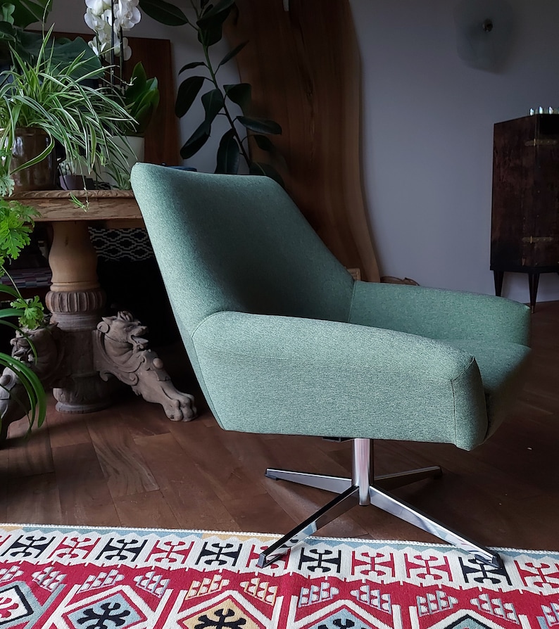 May include: A green swivel chair with a chrome base. The chair is upholstered in a soft, textured fabric. The chair is sitting on a rug with a colourful geometric pattern.