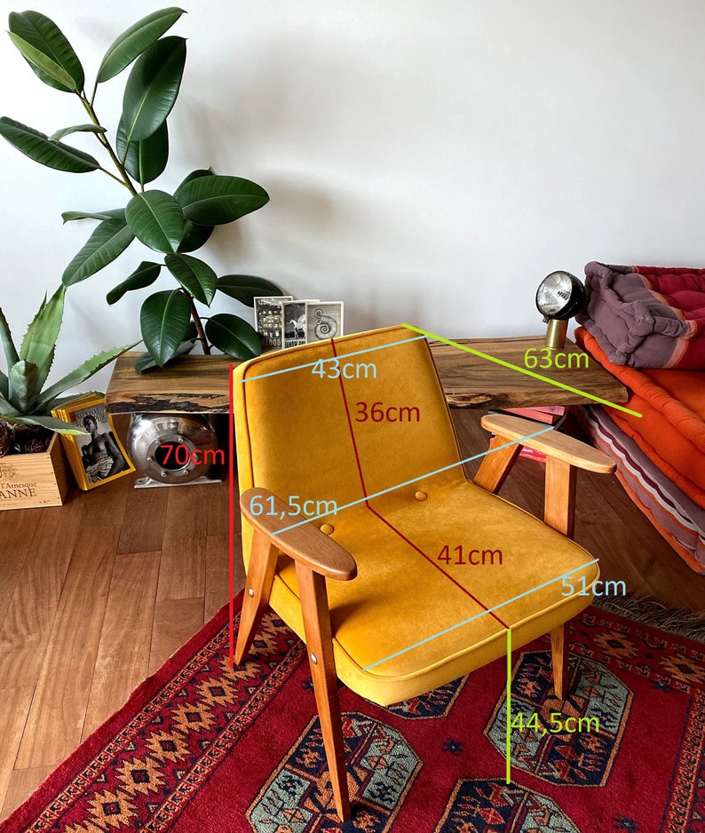 May include: A mustard yellow armchair with wooden legs and arms. The chair is 43 cm wide, 61.5 cm tall, and 51 cm deep. The seat is 41 cm wide and 36 cm deep.
