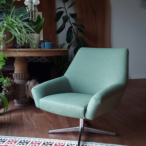 May include: A light green swivel chair with a modern design. The chair is sitting on a red and white patterned rug.