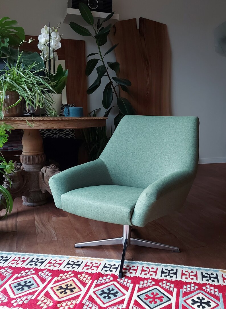 May include: A light green swivel chair with a modern design. The chair is sitting on a red and white patterned rug.