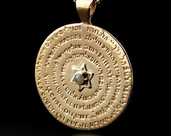May include: A gold-colored pendant necklace with a circular pendant featuring engraved text and a Star of David with a small, light-colored stone in the center. The necklace has a gold chain and a black background.