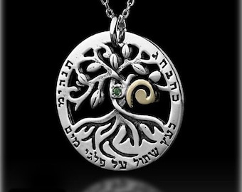 May include: Silver necklace with a round pendant featuring a tree of life design with Hebrew text. The pendant has a green gemstone and a gold swirl.