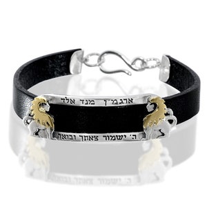May include: Black leather bracelet with a silver and gold lion design. The bracelet has Hebrew text that reads "אֱמֶת יִשְׁתַּבֵּחַ אֲדֹנָי בָּעַד זֹאת" which translates to "Truth, may God be praised for this".
