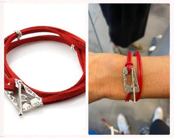 May include: Red leather bracelet with a silver charm featuring Hebrew text. The charm is shaped like a triangle with a small heart in the center.