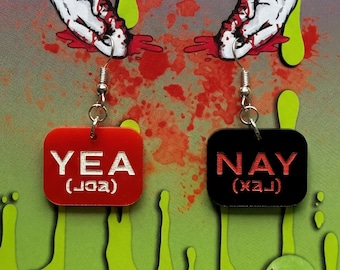 May include: A pair of novelty earrings on a display card. The earrings are red and black rectangles with the words "YEA" and "NAY" in white. The card has a green and purple design with the text "SEAGRIFFIN CREATIONS" and "HORROR".