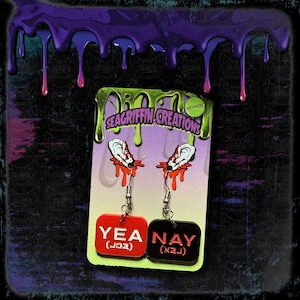 May include: A pair of horror-themed earrings. The earrings feature a red and black rectangular charm with the words 'YEA (jɔə)' and 'NAY (xæɪ)' in white. Above the charms are dangling silver hooks with a graphic of a bloody ear. The background is black with a dripping purple paint effect. Yea/Nay/MCR/The Black Parade/My Chemical Romance Earrings