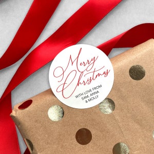 May include: White round gift tag with red cursive text that says "Merry Christmas" and the words "With love from Sam, Anna & Molly" in smaller red text.