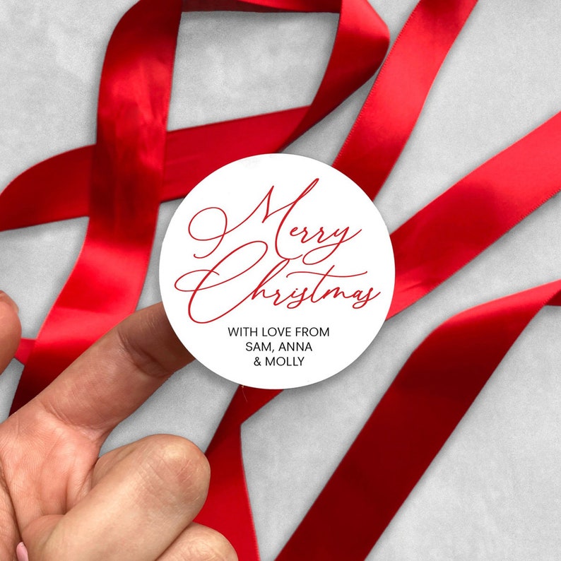 May include: White round sticker with red cursive text that says "Merry Christmas" and the words "With love from Sam, Anna & Molly" in black text.