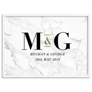 May include: White framed print with a marble background. The print features the letters "M & G" in black, with a gold glitter ampersand. Below the letters are the names "Meghan & George" and the date "30th May 2019".