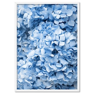 May include: A framed print showing a close-up of light blue hydrangea flowers. The flowers are densely packed with multiple petals, creating a textured appearance. The print is set in a white frame, offering a clean, modern aesthetic.