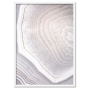 May include: A framed print displaying a detailed cross-section of an agate stone. The image reveals concentric bands of white, grey, and pale pink, producing a layered, textured appearance. The artwork is enclosed in a white frame, accentuating its contemporary style.