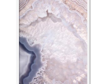 May include: Close-up of a pink and white agate geode with a purple and blue band. The geode has a natural, organic texture.