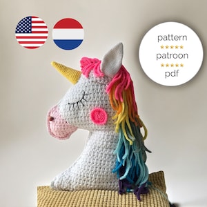 Op de afbeelding: Haakpatroon voor een eenhoornhoofd in het Engels en Nederlands. Het patroon bevat instructies voor het maken van een wit eenhoornhoofd met een regenboogmanen en een roze neus. Het patroon is beschikbaar als PDF-download.