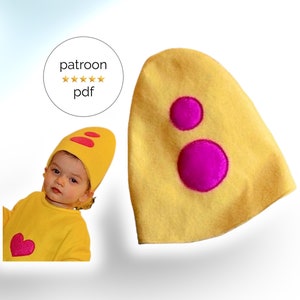 Op de afbeelding: Een gele vilt hoed met twee roze vilt cirkels. De hoed is eivormig en loopt spits toe. De hoed is voor een baby of peuter.