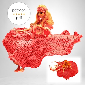 Op de afbeelding: Een rode gehaakte poppenjurk met een gerimpelde zoom. De jurk wordt gedragen door een pop met blond haar en een rood bloemenhoofdband. De pop zit op een witte achtergrond. De afbeelding bevat ook een kleinere afbeelding van de jurk op een pop.