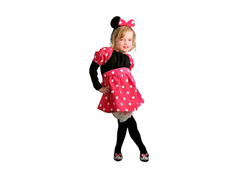 Op de afbeelding: Een jong meisje verkleed als Minnie Mouse. Ze draagt een zwart-wit geblokt jurkje met een zwarte strik op haar hoofd.