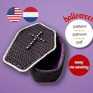 Op de afbeelding: Een gehaakte kist met een witte rand en een kruisontwerp op het deksel. De binnenkant is gevoerd met paarse stof. De afbeelding bevat het woord "Halloween" en de woorden "pattern", "patroon" en "pdf".