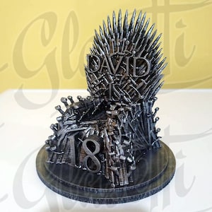 May include: A black 3D printed cake topper featuring a replica of the Iron Throne from the TV show Game of Thrones. The throne is decorated with the name "DAVID IS" and the number "18".
