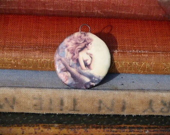 Handmade ceramic pendant with an illustration of a mermaid and fish