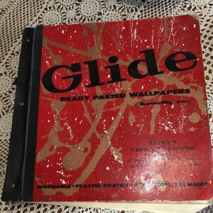 Może przedstawiać: Czerwono-biała książka z tytułem "Glide Ready Pasted Wallpapers" i tekstem "Nixon's Paints and Wallpapers" na okładce.