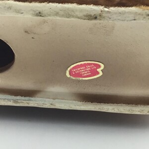May include: Close-up of a brown ceramic figurine with a red sticker that reads "Enterprise Sales & Distributors Ltd. Toronto Canada."