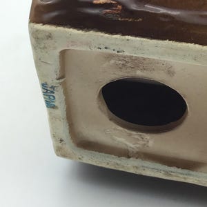 May include: A brown ceramic figurine with a hole in the bottom. The figurine has a brown glaze and the words "JAPAN" are printed on the bottom.