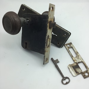 Può includere: Set di ferramenta per porte d'epoca con una maniglia per porte in metallo nero, una serratura e una chiave. Il set include una placca di battuta in porcellana bianca e una chiave.