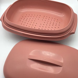 Puede incluir: Una vaporera rectangular de color rosa polvoriento con una tapa a juego. La vaporera tiene un inserto perforado para drenar y asas en los lados. La tapa tiene un asa elevada para facilitar la extracción. El juego está hecho de plástico duradero.