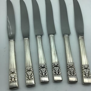 May include: Set of six silver-plated dinner knives with ornate floral designs on the handles.