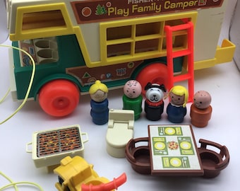 May include: A vintage Fisher-Price Play Family Camper toy set. The set includes a green and yellow camper, a boat, a motorcycle, a grill, a table, a toilet, and several small figures. The camper has a red ladder and orange wheels.
