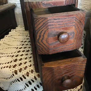 Gabinete de costura rústico de madera con dos cajones y frente en ángulo