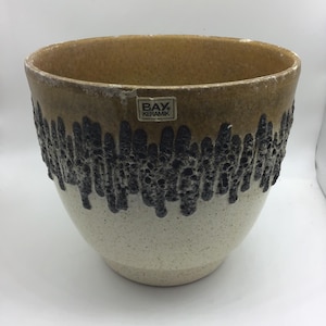 May include: A large, brown and white ceramic planter with a black, textured design around the middle. The planter has a label that reads "BAY. KERAMIK".