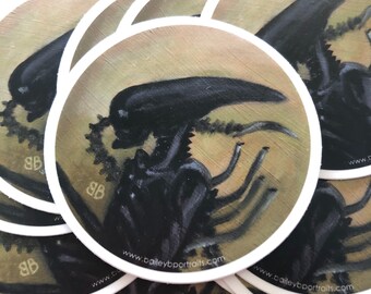 May include: A stack of round stickers featuring a black and grey alien creature with a textured background. The stickers have a white border and the text "www.baileybportraits.com" is printed on the bottom.