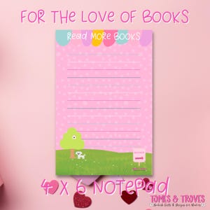 Könnte beinhalten: Rosa 10 x 15 cm Notizblock mit gepunktetem Muster und linierten Seiten. Der Notizblock zeigt eine grüne Wiese mit einem Baum, einem Hund und dem Text "Read MORE BOOKS". Entworfen für Bücherliebhaber.